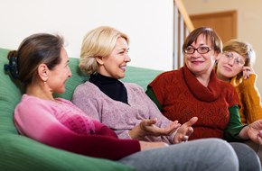 Four women chatting on a sofa