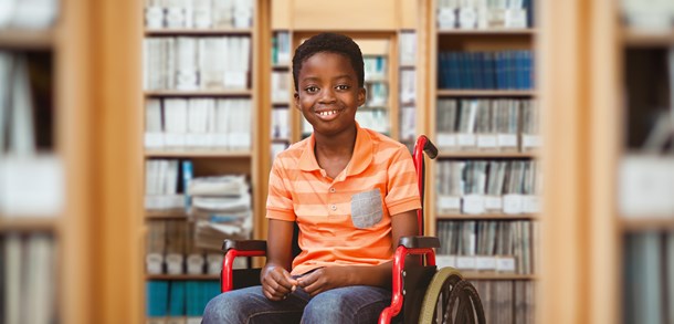 Young boy sitting in a wheel chair smiling at the camera