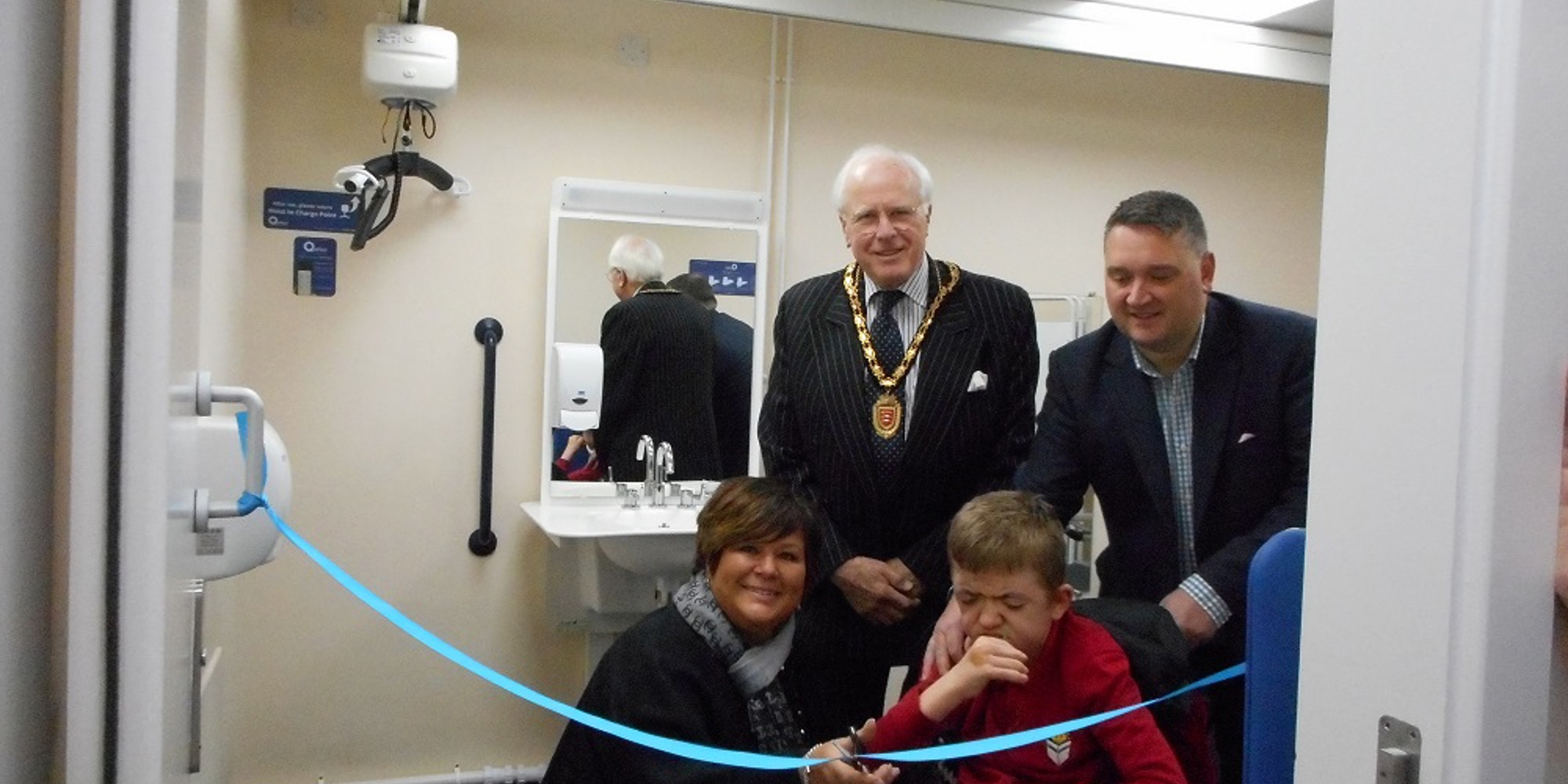 cutting the ribbon to open the changing places facility with people and mayor in the background