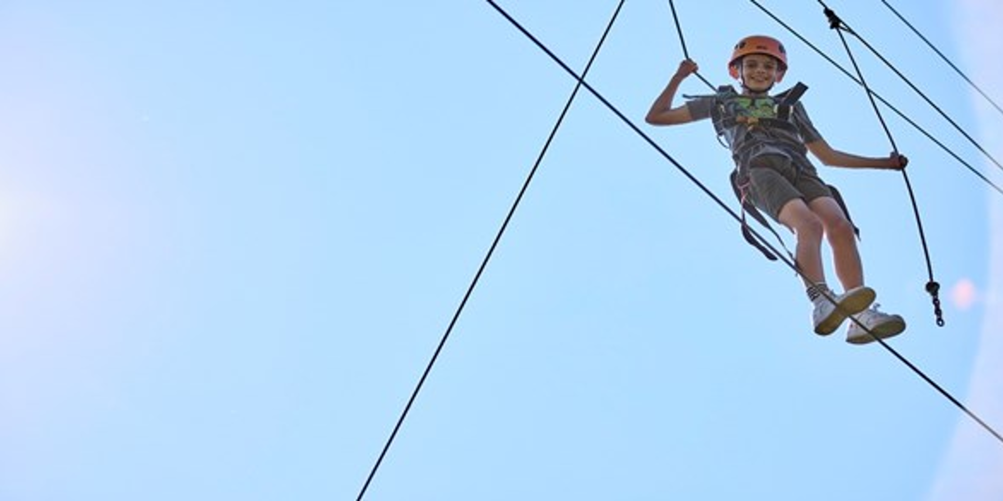 Child smiling on tightrope in harness