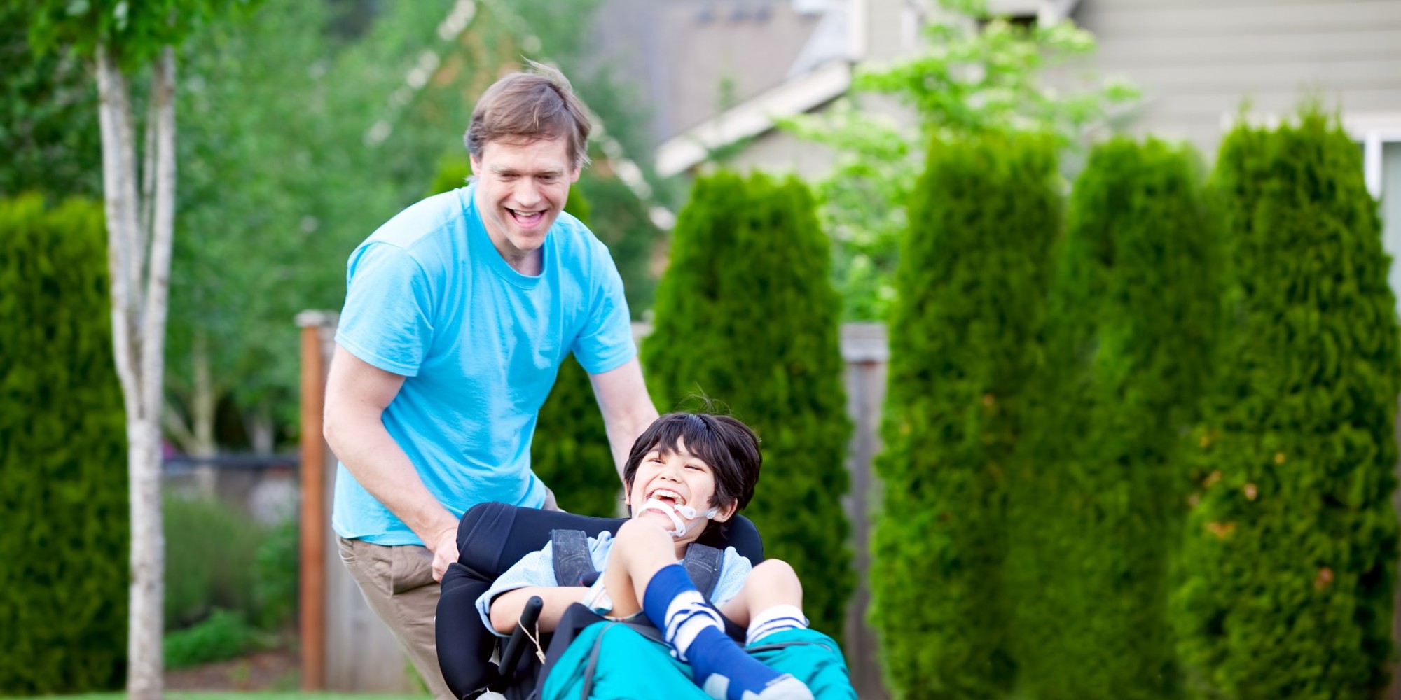 A dad pushing a chair in a wheelchair both laughing